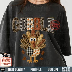 Könnte beinhalten: Dunkelgraues T-Shirt mit dem Wort "GOBBLE" in einer Mischung aus Leopardenmuster, Karomuster und Kürbismotiven. Unter dem Wort befindet sich ein Truthahn mit Patchwork-Design und Herbstblättern. Das Shirt hat einen Vintage-Look.
