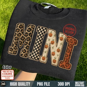 May include: Black sweatshirt with the word "MINI" in a variety of patterns. The letters are leopard print, checkered, pumpkin-themed, and leopard print. The sweatshirt has the text "ORIGINAL DESIGN" in a red circle.