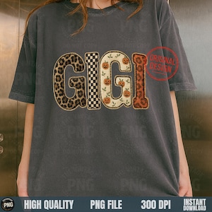 May include: A gray t-shirt with the word "GIGI" in a decorative design. The letters feature a leopard print, a black and white checkerboard pattern, and pumpkins. A red "ORIGINAL DESIGN" stamp is visible.