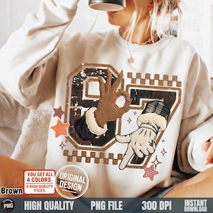 May include: Cream-colored sweatshirt featuring a graphic of two cartoon hands forming the 'OK' gesture. The design includes the number '67' in a distressed style, with star accents. The text on the image says "YOU GET ALL 4 COLORS", "ORIGINAL DESIGN", "HIGH QUALITY", "PNG FILE", "300 DPI", and "INSTANT DOWNLOAD".