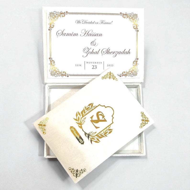 May include: A white wedding invitation box with gold decorative accents and text. The invitation card features the names "Samim Hasan & Zohal Sherzadah" and the date "November 23, 2025". The card inside has a gold emblem.