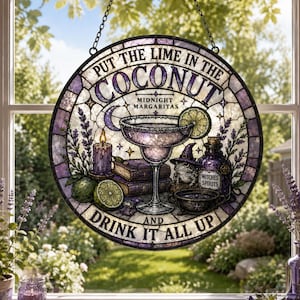 May include: A round stained glass suncatcher featuring a margarita glass, a lime, a candle, books, a frog wearing a witch hat, and a bottle labeled Witches Spirits. The text reads: PUT THE LIME IN THE COCONUT MIDNIGHT MARGARITAS AND DRINK IT ALL UP.