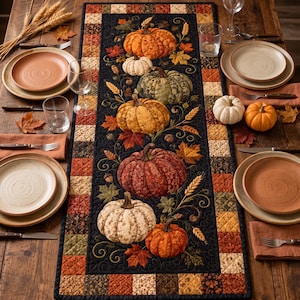 May include: A rectangular quilted table runner featuring a black center panel decorated with various pumpkins, autumn leaves, and wheat stalks. The border consists of a patchwork pattern in shades of orange, brown, and tan, creating a seasonal display.