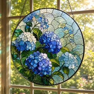 May include: Round stained glass window art featuring a vibrant hydrangea design. The artwork showcases blue and white hydrangea blooms with green leaves, set against a textured, light blue background. A black metal frame and hanging chain complete the piece.