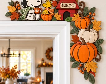 May include: A wooden door corner decoration featuring Snoopy holding a mug and Woodstock sitting on a pumpkin next to a red doghouse with the text Hello Fall. The design includes orange pumpkins, green leaves, and brown vines in an autumn theme.