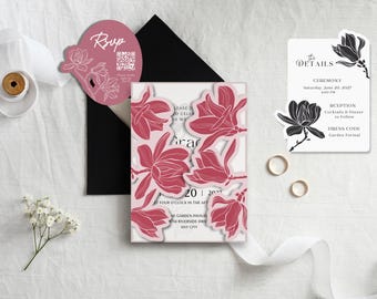 Könnte beinhalten: Ein Hochzeitseinladungsset mit einer zentralen Karte mit ausgestanzten rosa Magnolienblüten, einem schwarzen Umschlag, einer runden rosa RSVP-Karte mit QR-Code und einer weißen Detailkarte mit schwarzen Magnolienillustrationen und Text zum 20. Juni 2027.