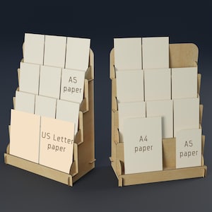 May include: Two wooden display stands with multiple shelves, each holding stacks of paper. One stand displays US Letter and A5 paper, while the other holds A4 and A5 paper. The stands are made of light brown wood.