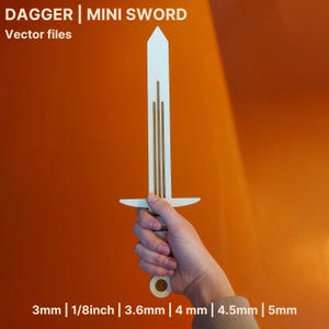May include: A white mini sword with a crossguard and a pointed tip. The sword has three vertical brown lines down the center. The text "DAGGER | MINI SWORD" and "Vector files" is at the top. The sword is 1/8 inch thick.