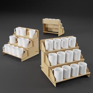 Könnte beinhalten: Mehrere weiße Keramikbecher werden auf gestaffelten Holz-Präsentationsständern präsentiert. Die Ständer bestehen aus hellfarbigem Holz und haben ein abgestuftes Design. Die Becher sind in Reihen angeordnet, um ihre Form hervorzuheben. Der Hintergrund ist dunkelgrau.