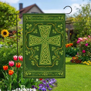 May include: A green garden flag featuring a Celtic cross design with intricate knotwork and shamrock accents. The cross is in shades of yellow and green, set against a darker green background. The flag is displayed in a garden setting with flowers and greenery.
