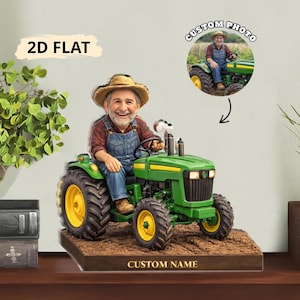 May include: A 2D flat personalized figurine of a man on a green tractor with yellow wheels. The figurine has the text "CUSTOM NAME" at the base and "CUSTOM PHOTO" in a circle above. The figurine is a unique gift.