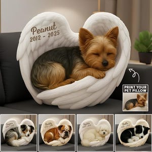 Puede incluir: Un cojín conmemorativo para mascotas personalizado en forma de alas de ángel, con un Yorkshire Terrier durmiendo. El cojín blanco tiene el nombre y las fechas de la mascota impresos en las alas. También se muestran cojines adicionales con diferentes razas de perros.