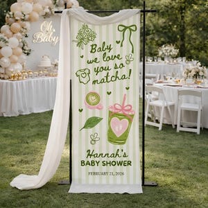 May include: A vertical banner with a green and white striped background, featuring the text "Baby we love you so matcha!" and "Hannah's BABY SHOWER FEBRUARY 21, 2026." The banner includes illustrations of a baby onesie, a cup of matcha, and a matcha drink.
