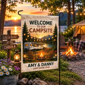 May include: A rectangular garden flag featuring a printed campsite scene with a camper, campfire, and two chairs. The text reads Welcome to our Campsite, Amy & Danny, and Lake Tahoe 2036. The flag is suspended from a black metal garden flag stand.