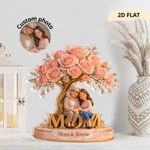 Könnte beinhalten: Dekorative Figur mit Mutter und Tochter unter einem Baum aus rosa Rosen. Die Basis trägt in goldener Schrift die Aufschrift "MOM", darunter "Mom & Jennie". Ein kreisförmiges Foto befindet sich in der oberen linken Ecke mit dem Text "Custom photo".
