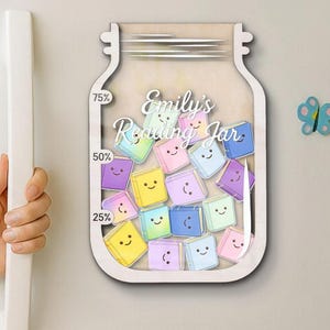 以下が含まれることがあります： 「Emily's Reading Jar」の文字が入った、木製の瓶型の読書チャート。瓶の中には、25％、50％、75％のパーセンテージが記された、カラフルで笑顔のブック型のトークンが詰められています。