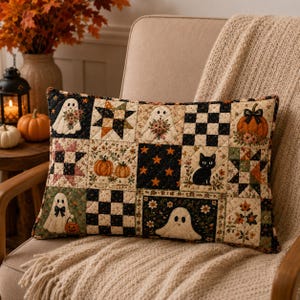 May include: A rectangular quilted throw pillow featuring a patchwork design with various autumn and Halloween motifs, including white ghosts, orange pumpkins, a black cat, star patterns, and black and white checkered squares with floral accents.
