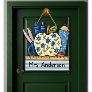 May include: A wooden teacher's door sign featuring an apple with blue flowers, scissors, crayons, and a pencil. The sign includes a ruler and the name "Mrs. Anderson" in blue lettering. The sign is hanging on a green door.