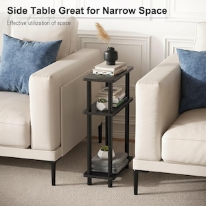 May include: A black, three-tiered side table with a narrow design, ideal for small spaces. The table holds books, a small plant, and decorative items. The text at the top reads "Side Table Great for Narrow Space."