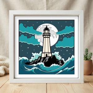 May include: A square framed wall art piece featuring a layered paper-cut style illustration of a white lighthouse on a dark rocky island. The scene includes a large full moon, teal clouds, a dark blue starry night sky, and stylized teal ocean waves.