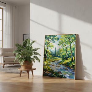 May include: A framed landscape painting depicts a serene river scene. The artwork features a vibrant palette of greens, blues, and yellows, with trees lining the riverbanks. The painting is displayed in a room with a plant and a chair.