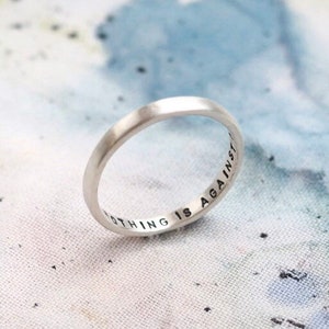 May include: A silver band ring with the inscription "Nothing is again in sight" engraved on the inside.