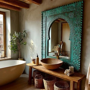 May include: A bathroom with a large, oval-shaped bathtub and a wooden vanity with a wooden bowl sink. A large, ornate, turquoise-colored mirror hangs above the vanity. A window with a view of a brick wall is on the left.