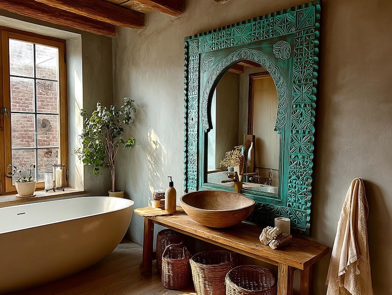 May include: A bathroom with a large, oval-shaped bathtub and a wooden vanity with a wooden bowl sink. A large, ornate, turquoise-colored mirror hangs above the vanity. A window with a view of a brick wall is on the left.