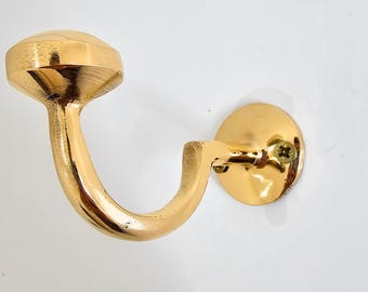 May include: A gold-colored, decorative hook with a rounded, faceted top and a curved arm. The hook is mounted on a circular base with a screw. The hardware is designed for hanging items.