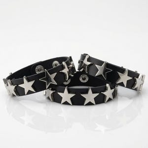 May include: Three black leather bracelets featuring silver-toned metal star-shaped studs arranged in a row. Each bracelet is secured with a circular metal snap button closure, providing a consistent look across all three pieces of wrist jewelry.