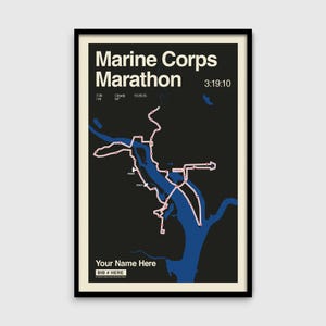 May include: A framed poster featuring the Marine Corps Marathon route map. The poster has a black background with a blue route map and white text. The text includes "Marine Corps Marathon", time, and runner details.