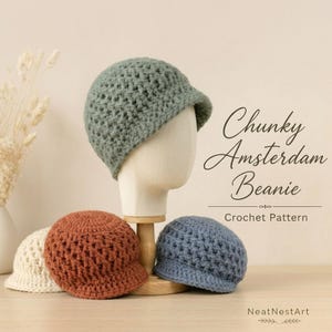 May include: A chunky crochet beanie with a short brim, displayed in sage green on a mannequin head, with additional beanies in cream, rust orange, and dusty blue. The text reads Chunky Amsterdam Beanie Crochet Pattern by NeatNestArt.