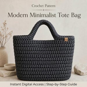 Puede incluir: Un bolso tote de ganchillo gris oscuro, de forma rectangular con asas redondeadas. El bolso presenta un patrón de puntadas texturizadas y una pequeña etiqueta rectangular que dice "Hand Made". El texto "Crochet Pattern" y "Modern Minimalist Tote Bag" se muestra.