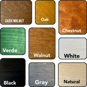 May include: A collection of nine square wooden samples showcasing various stain colors. Colors include Dark Walnut, Oak, Chestnut, Verde, Walnut, White, Black, Gray, and Natural, each labeled with its name.