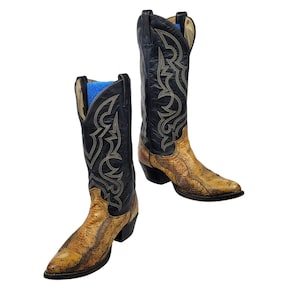 May include: A pair of cowboy boots with a snakeskin pattern on the foot and a black shaft with decorative stitching. The boots have a pointed toe and a stacked heel, showcasing a classic Western style.