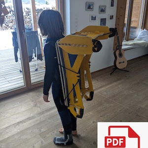 May include: A yellow and blue backpack-like structure with black straps is being worn. The structure has a geometric design and appears to be made of wood or a similar material. The person is wearing a black and blue outfit.