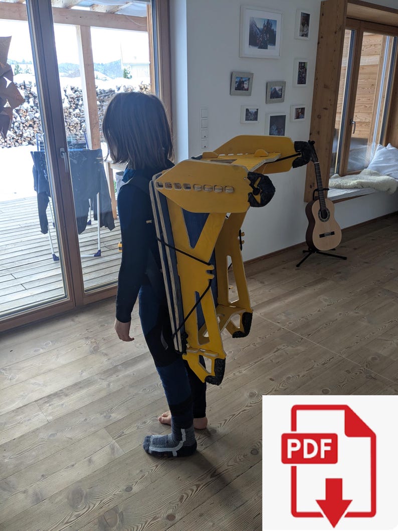 May include: A yellow and blue backpack-like structure with black straps is being worn. The structure has a geometric design and appears to be made of wood or a similar material. The person is wearing a black and blue outfit.