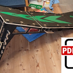 May include: A black and wood-toned ramp with green arrow designs and the text "AIR TIME" is shown. The ramp is folded and has a PDF icon in the lower right corner. The ramp is on a wooden floor.