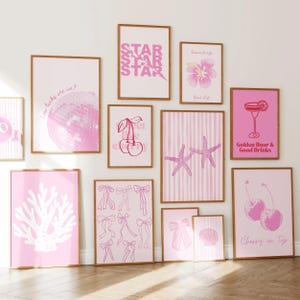 May include: A gallery wall set of eleven framed art prints in shades of pink and white. The collection features illustrations of a disco ball, cherries, a hibiscus flower, starfish, bows, a seashell, and coral, with text including "Golden Hour & Good Drinks".