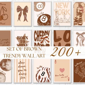 May include: A collection of wall art prints featuring brown and beige tones. Designs include cherries, bows, billiard balls, the New York City skyline, disco balls, cowboy boots, playing cards, and various typography like Born to Shine and Love.