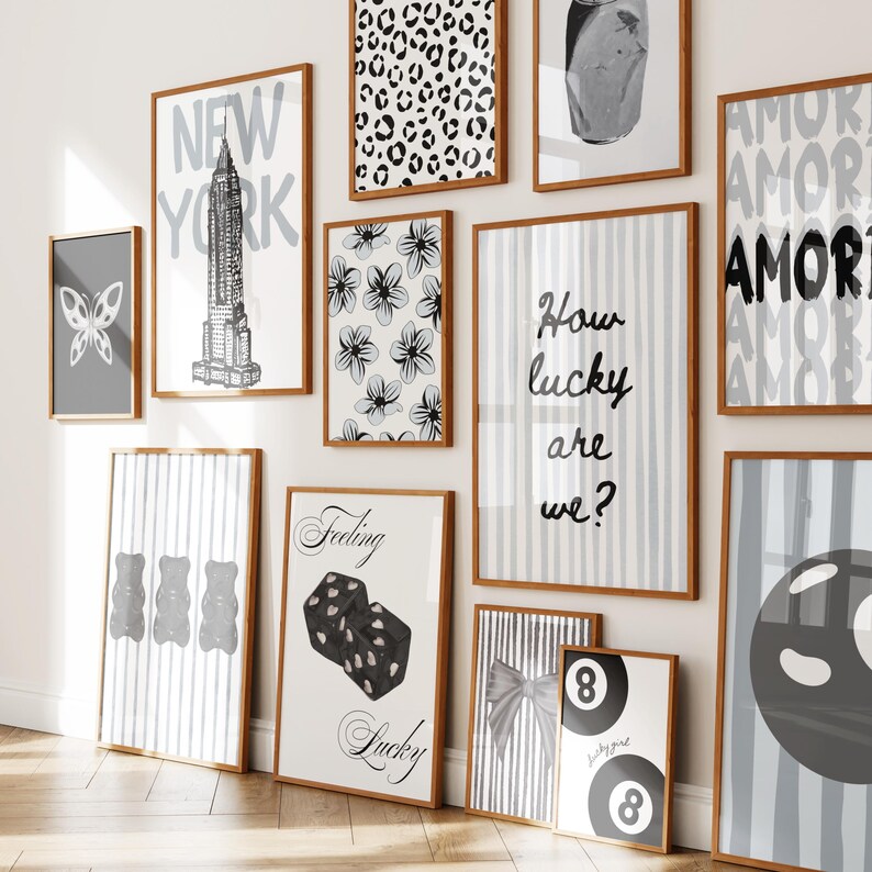 Pu&ograve; includere: Una collezione di stampe artistiche incorniciate in vari formati e design. Le stampe presentano una farfalla, lo skyline di New York, motivi floreali e il testo che recita "How lucky are we?" e "Feeling Lucky". La tavolozza dei colori &egrave; principalmente bianco, nero e grigio.