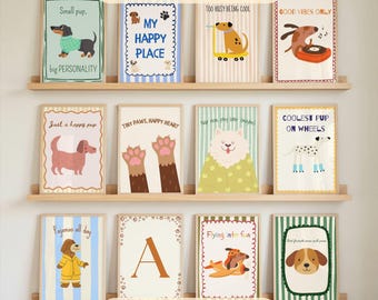 May include: A collection of framed dog-themed prints displayed on wooden shelves. The prints feature various dog illustrations with phrases like "My Happy Place" and "Coolest Pup on Wheels." The text "50+ PRINTS" and "DOG - KIDS" are also visible.