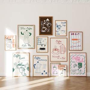 May include: A collection of framed coffee-themed art prints. The prints feature illustrations of coffee makers, cups, and phrases like "Coffee Time" and "Coffee Club." The color palette includes brown, blue, and pink tones.