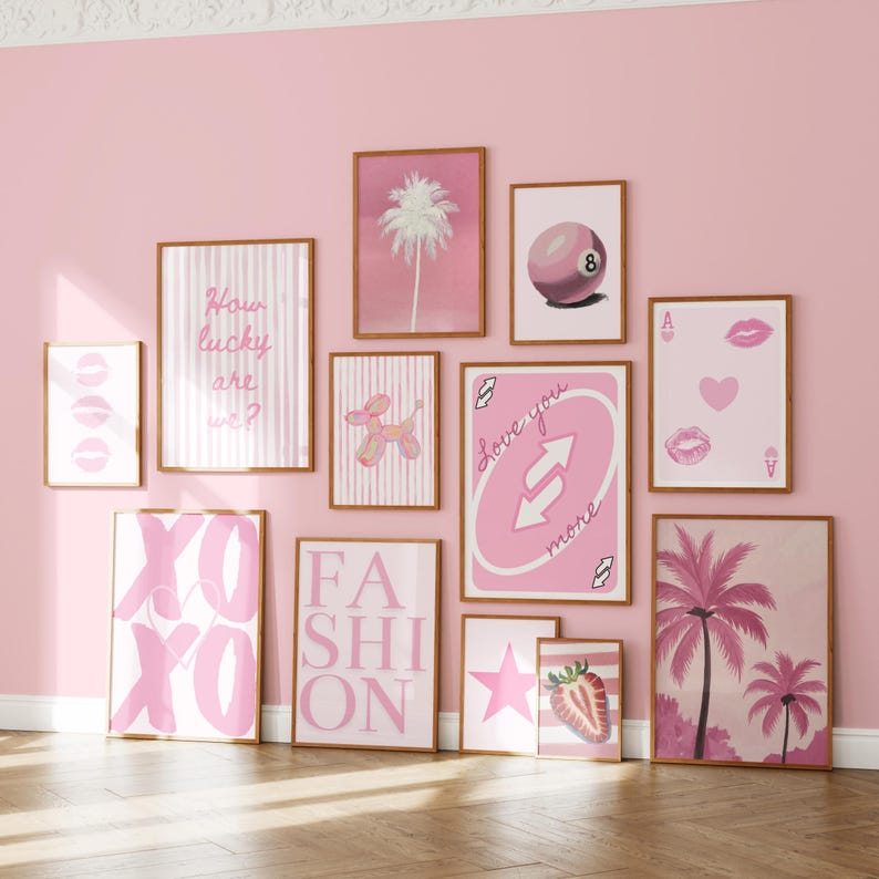 Puede incluir: Un conjunto de pared de galer&iacute;a con once l&aacute;minas enmarcadas con ilustraciones en tonos rosa, incluyendo una palmera, una bola de billar ocho, un perro globo, una carta de juego, una fresa, una estrella y texto que dice How lucky are we, XOXO y FASHION.