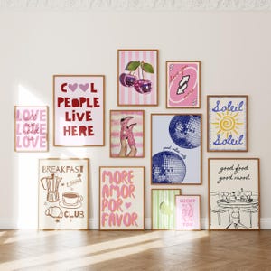 May include: A collection of framed art prints with various designs and text. The prints feature phrases like "Cool People Live Here" and "Love You More", along with illustrations of cherries, disco balls, and a sun. The frames are a warm brown.