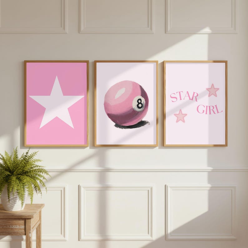 Puede incluir: Un conjunto de tres l&aacute;minas de pared enmarcadas en madera clara. La l&aacute;mina de la izquierda muestra una gran estrella blanca sobre fondo rosa. La central presenta una bola de billar rosa con el n&uacute;mero ocho. La de la derecha incluye el texto STAR GIRL.