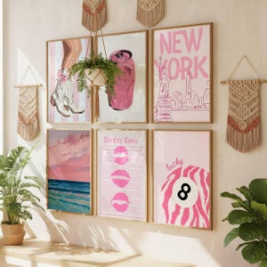 Puede incluir: Un conjunto de seis l&aacute;minas enmarcadas con ilustraciones en tonos rosas que incluyen botas vaqueras, una lata de refresco, el horizonte de Nueva York, una puesta de sol sobre el mar, una p&aacute;gina de peri&oacute;dico The City Times y una bola ocho.
