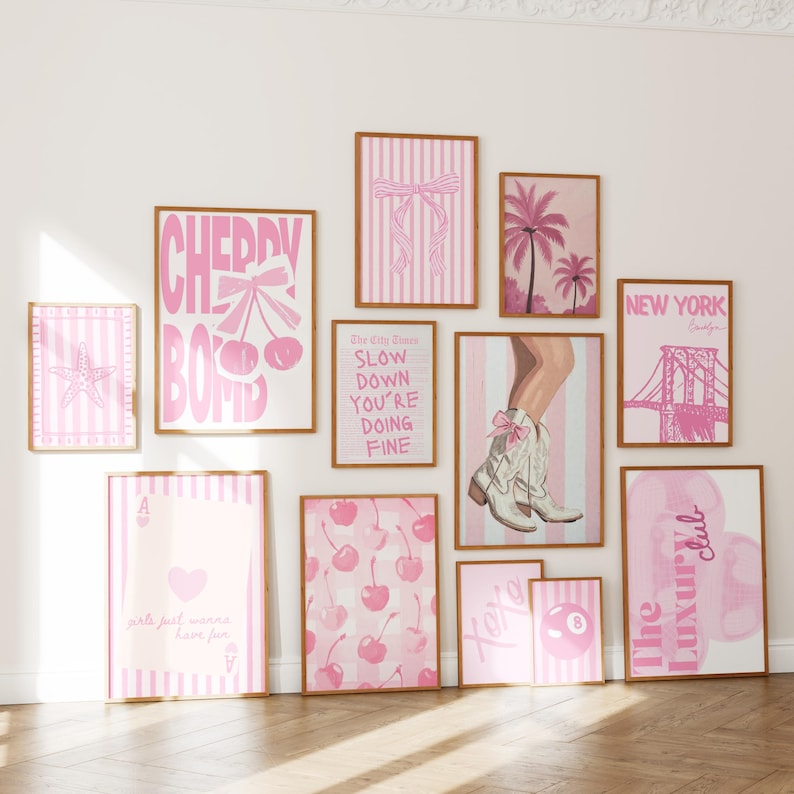 Puede incluir: Un conjunto de once l&aacute;minas art&iacute;sticas enmarcadas en tonos rosa y blanco. La colecci&oacute;n incluye ilustraciones de cerezas, una estrella de mar, palmeras, una bota vaquera, un puente, una carta de juego, una bola de billar y varios textos.