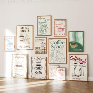 May include: A collection of framed art prints with coffee-themed illustrations and text. The prints feature drawings of coffee cups, espresso machines, and phrases like "Coffee Addicts" and "Coffee Space." The frames are a warm brown color.