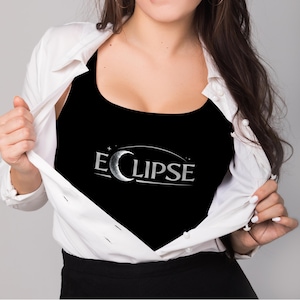 Puede incluir: Camiseta sin mangas negra con la palabra "ECLIPSE" en letras plateadas, con un diseño de luna creciente y estrellas. La camiseta sin mangas se lleva debajo de una camisa blanca abotonada.